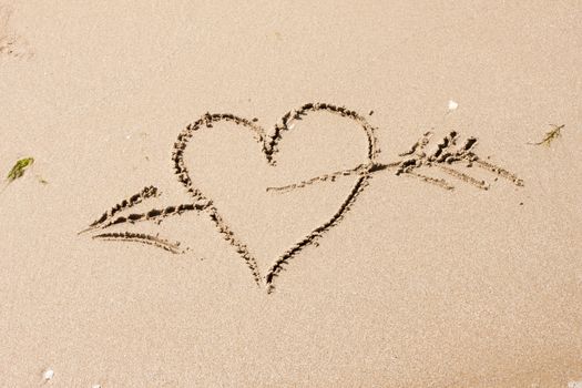 heart with an arrow written on the sandy beach with wave