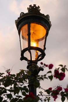 Old fashioned street lamp just being lit in the early evening (shallow depth of field)