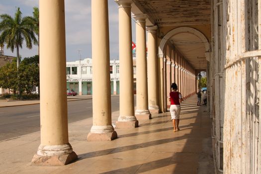 People waking under architectural arches in Cienfuegos, Cuba
