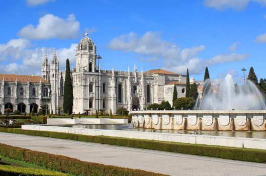 The Mosteiro or monastery dos Jeronimos displaying Manueline architecture with fountain from Praca do Imperio gardens, Portugal
