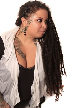 Beautiful ethnic curvaceous woman with long dreadlocks, tattoos and piercings, on a white background