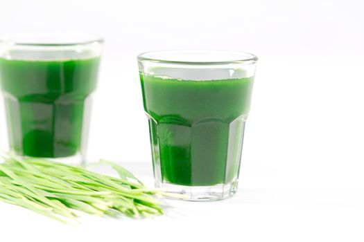 Wheat grass juice with fresh wheat grass on white background
