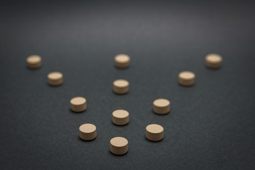 Some pills aligned in the form of flecla isolated on black background