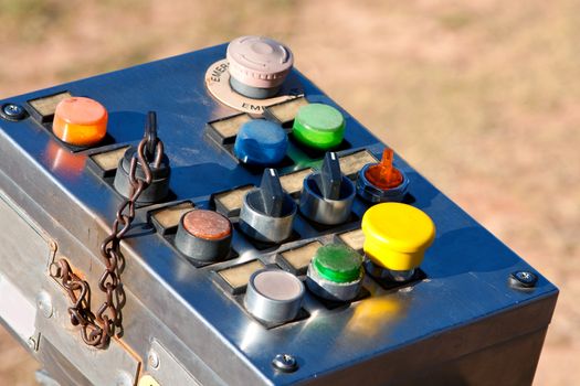 An old-fashioned industrial control panel with multi-colored buttons and switches, used to control a ride at a county fair.