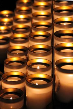 Lit candles in glasses on several rows