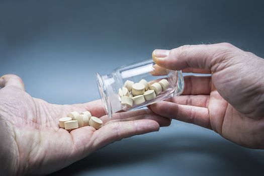 medical pills in a hand poured from a bottle transparent container