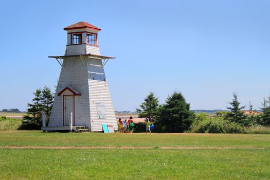 Lighthouse at Cabot Beach with beachgoers in Prince Edward Island, Canada