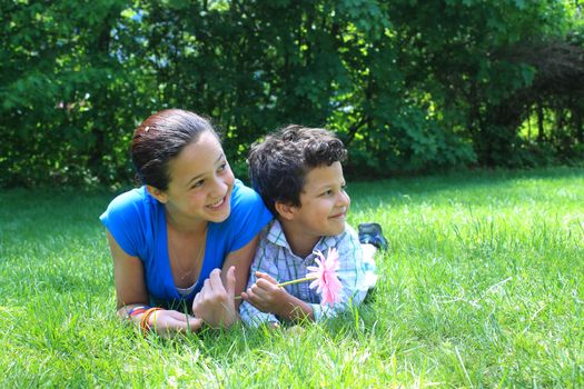  brother and  sister laying on the grass in the park