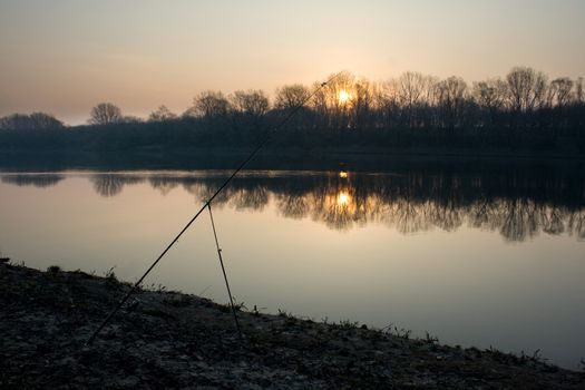 Dawn on the river in early spring. Abandoned fishing rod to catch fish