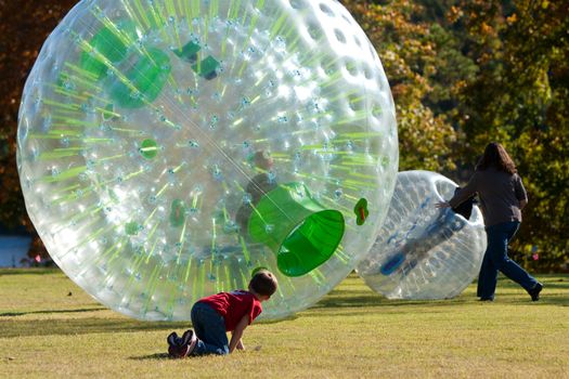 Flowery Branch, GA, USA - October 15, 2011:  A mother and child get involved in pushing another child around in a zorb at a fall festival in Flowery Branch. 