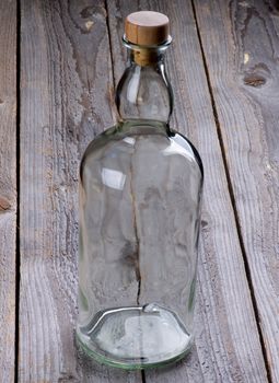 Empty Glass Groceries Bottle with Cork Stopper isolated on Rustic Wooden background