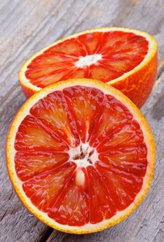 Two Halves of Ripe Blood Oranges closeup on Rustic Wooden background