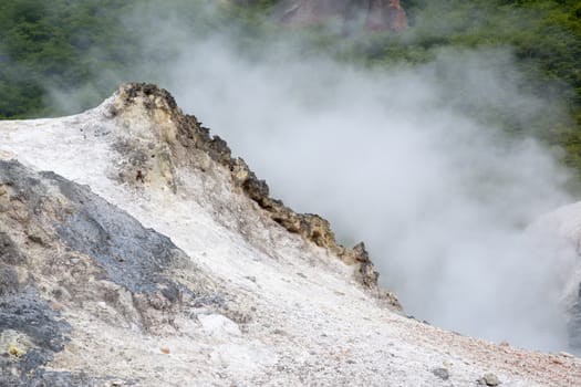 colorful volcanic land with hot steam behind colorful mineral sands