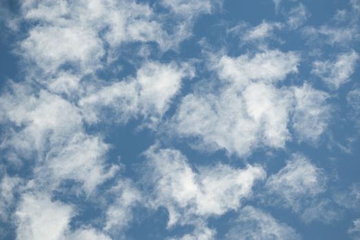 white clouds with  torn edges over blue sky background