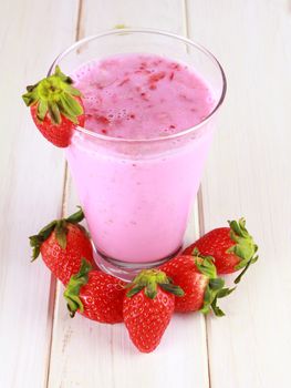 glass of strawberry smoothie on a white wooden background