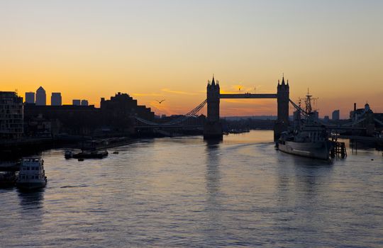 The beautiful sunrise behind Tower Bridge in London.  HMS Belfast and the skyscrapers in Docklands are also visible.