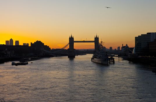 The beautiful sunrise behind Tower Bridge in London.  HMS Belfast, City Hall and the skyscrapers in Docklands are also visible.