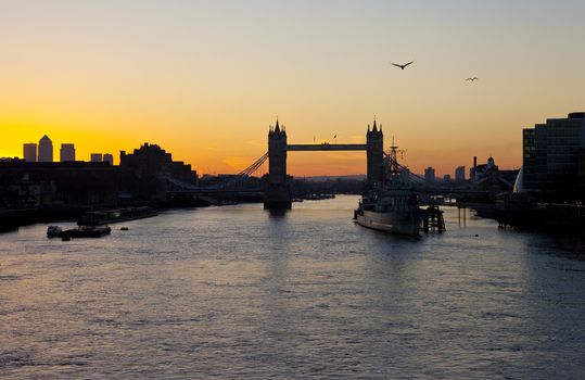 The beautiful sunrise behind Tower Bridge in London.  HMS Belfast, City Hall and the skyscrapers in Docklands are also visible.
