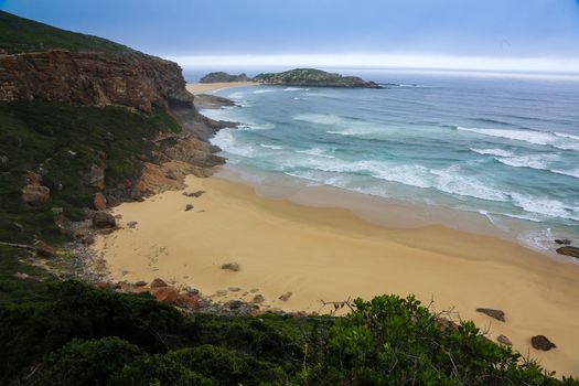 Rough sea and golden sand at the rugged coast in South Africa