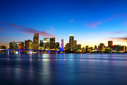 Miami city skyline panorama at dusk with urban skyscrapers over sea with reflection 