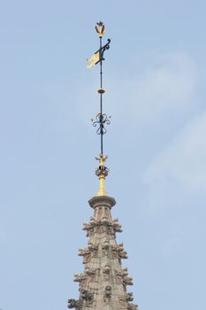 Spire with gold-trimmed weathercock, and blue sky in background