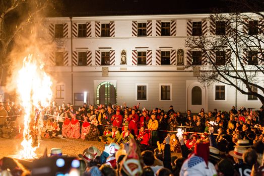 NEUHAUSEN, GERMANY ��� MARCH 4, 2014: Masked people are celebrating the end of carnival (fasnet) season by burning a puppet that is wearing a traditional costume (called the ���H��s���) symbolizing carnival on March 4, 2014 in Neuhausen (near Stuttgart), Germany. Carnival has a very long tradition in Neuhausen with influences of the swabian alemanisch culture that can be seen by the wooden masks people are wearing as part of their costumes.