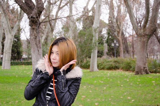 Asian woman wearing a winter coat standing in the garden.