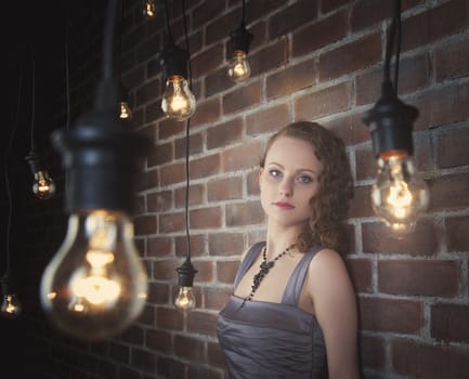 woman on a background of a wall from a brick and light bulbs