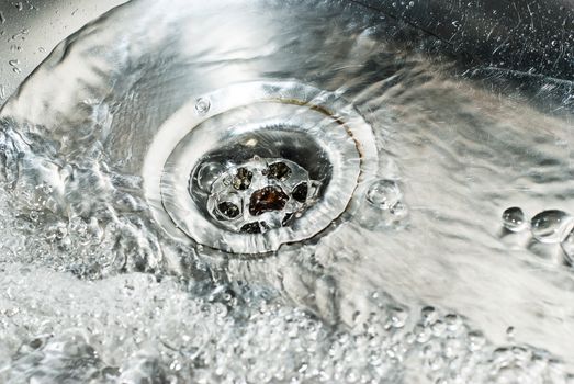 Stainless steel sink plug hole close up with water