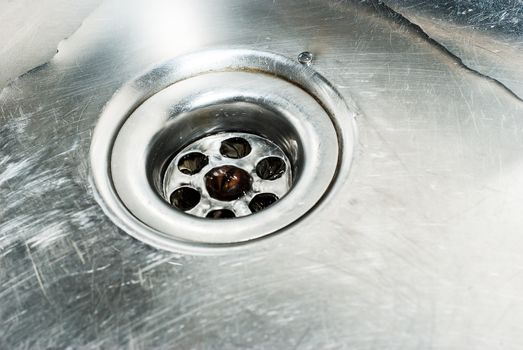 Stainless steel sink plug hole close up with water