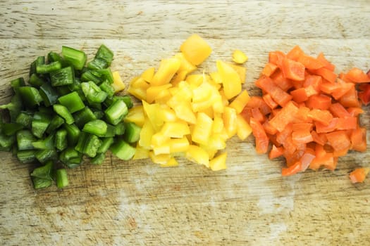 slices of colorful sweet bell pepper on wood board.