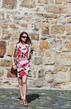 Young woman walking in the city and checking her mobile.