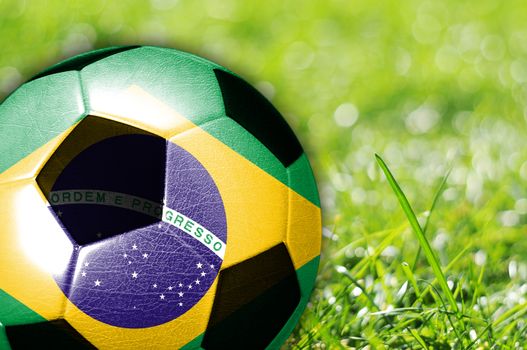 Soccer ball on grass with flag of Brazil painted on it