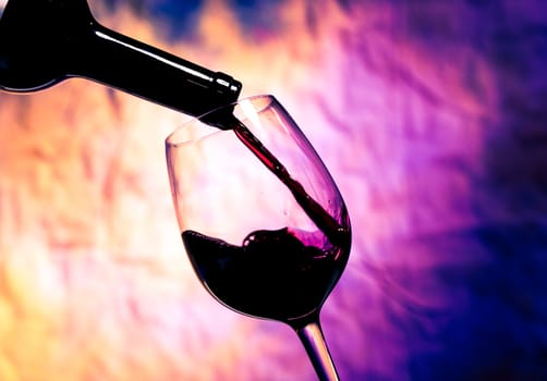 Red Wine Poured into Wineglass on background grunge bright multicolored