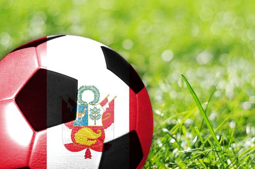 Soccer ball on grass with flag of Peru painted on it
