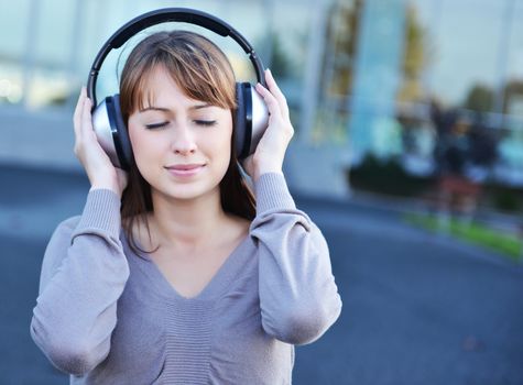 Beautiful girl in headphones over urban background