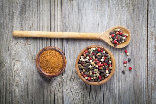 pepper spice in wooden bowl with spoon, on wooden background