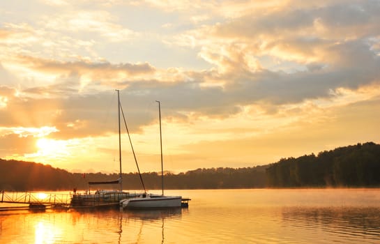 Summer landscape - sunset over lake with boats
