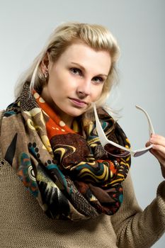 close up studio portrait of beautiful woman with sweater, scarf and sun glasses