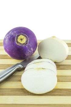 purple headed turnips with slices and knife on wood board.