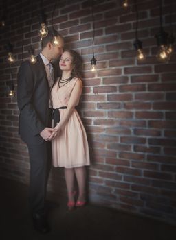 loving couple in the background of walls from a brick and light bulbs