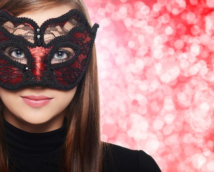 Beautiful woman in carnival mask over red bokeh background