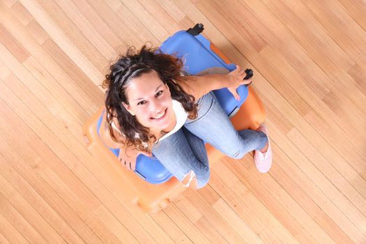 A young woman sitting on a stack of suitcases.