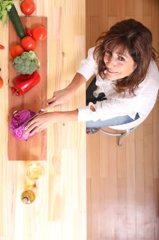 A beautiful mature woman cutting vegetables in the kitchen.