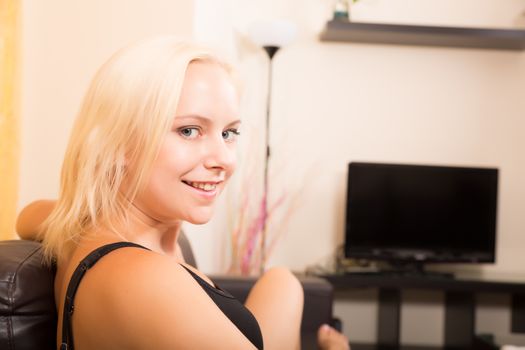 A blonde girl relaxing on a Sofa.