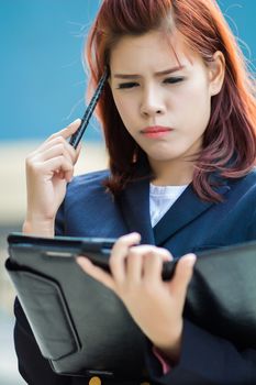 asian Businesswoman thinking with pen and holding document file.