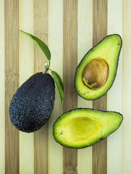 Avocados with leaves on a Dish of straw.