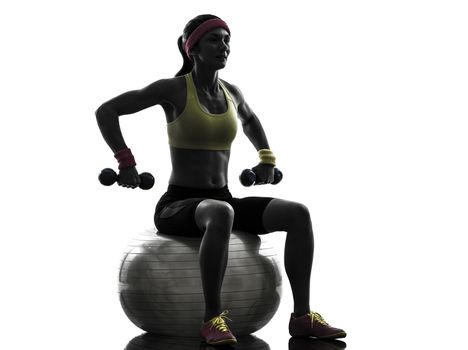 one woman exercising weight training on fitness ball in silhouette on white background