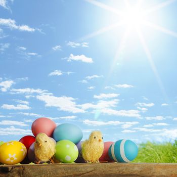 Easter eggs and chickens on green grass and sky background