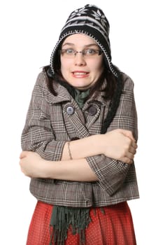 Young woman shaking from the cold on a white background wearing a wool hat and scarf 